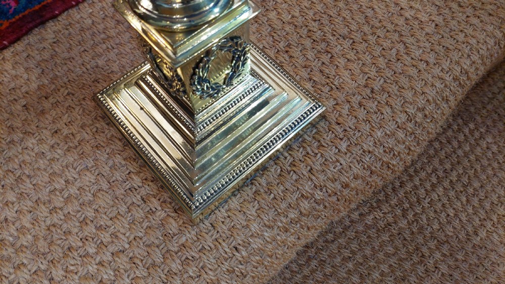 An early 20th-century brass table lamp featuring a fluted Corinthian column base on a stepped pedestal, topped with a cream domed shade trimmed with fringe and tassels. View VI