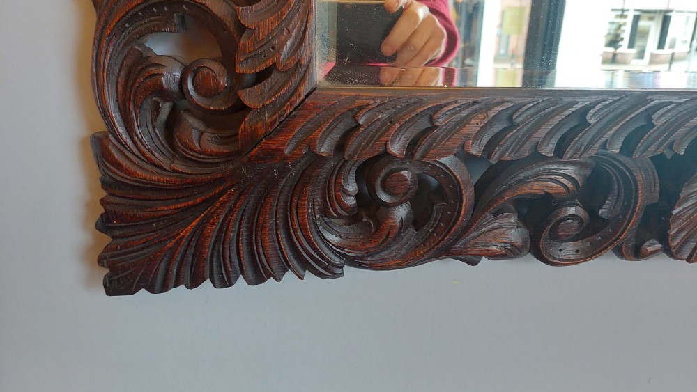 A 19th-century rectangular wall mirror featuring a heavily carved dark oak frame decorated with acanthus leaves and scroll motifs. View II
