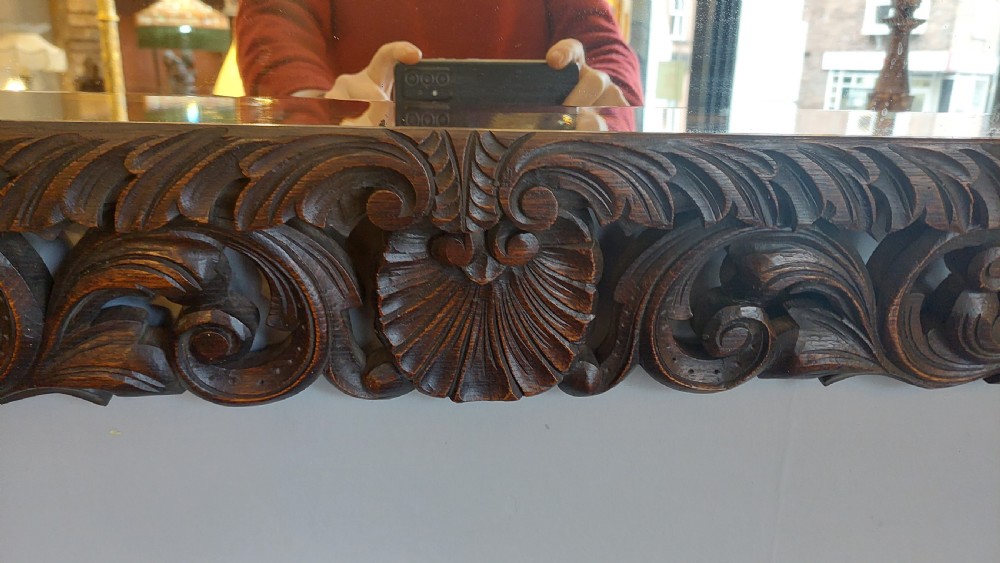A 19th-century rectangular wall mirror featuring a heavily carved dark oak frame decorated with acanthus leaves and scroll motifs. View IV