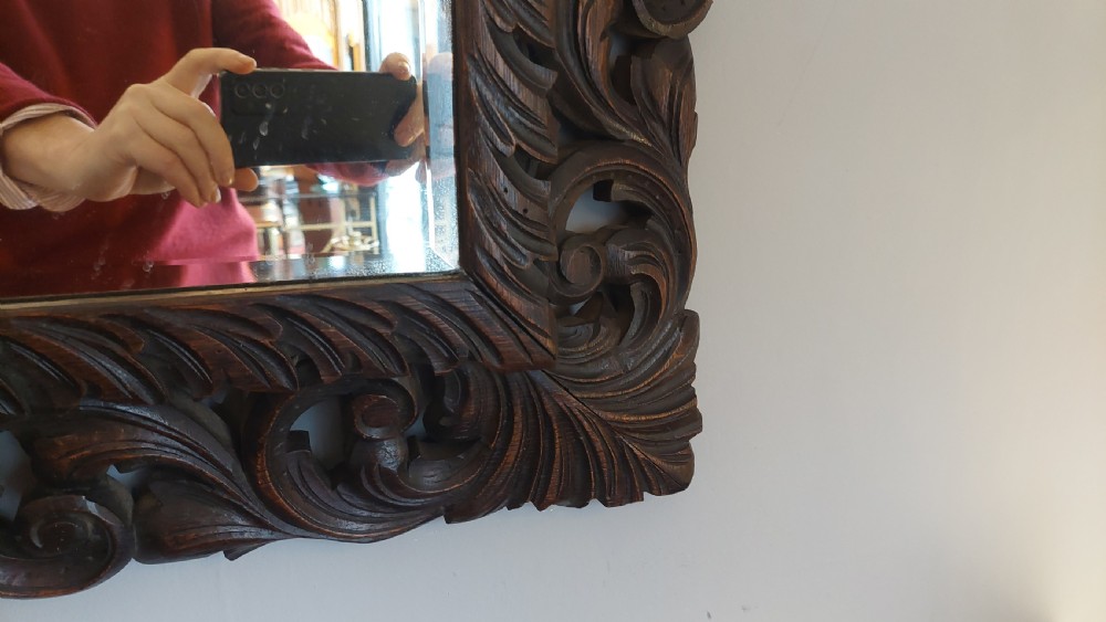 A 19th-century rectangular wall mirror featuring a heavily carved dark oak frame decorated with acanthus leaves and scroll motifs. View V