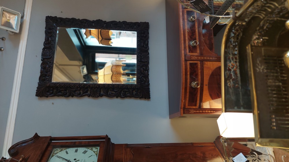 A 19th-century rectangular wall mirror featuring a heavily carved dark oak frame decorated with acanthus leaves and scroll motifs. View VII
