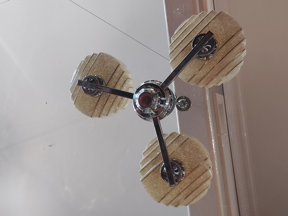 A three-arm Art Deco ceiling light fixture featuring chrome metalwork, reddish bakelite collars, and three mottled cream and amber glass bowl shades. View II