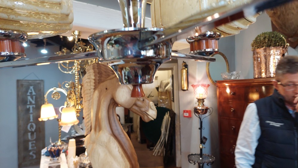 A three-arm Art Deco ceiling light fixture featuring chrome metalwork, reddish bakelite collars, and three mottled cream and amber glass bowl shades. View V