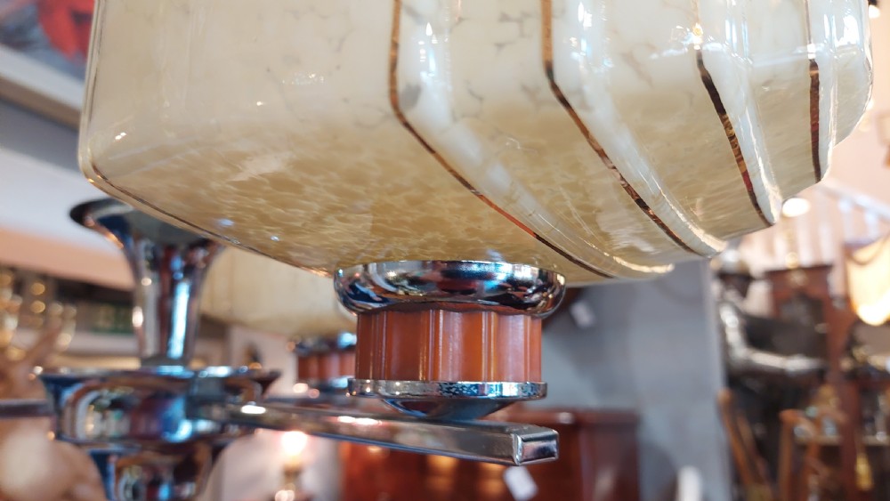 A three-arm Art Deco ceiling light fixture featuring chrome metalwork, reddish bakelite collars, and three mottled cream and amber glass bowl shades. View VIII