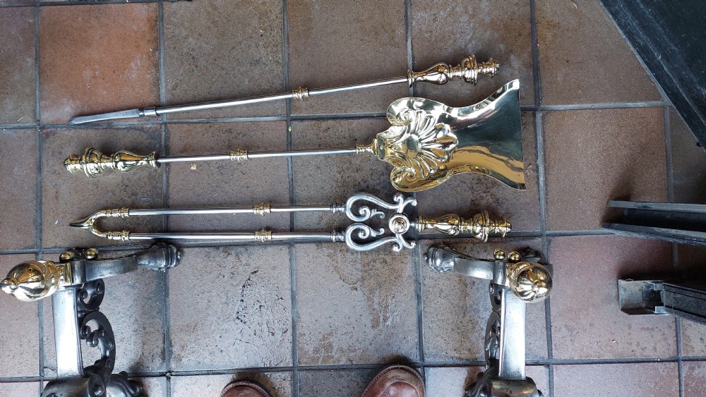 A set of Victorian hearth accessories comprising three metal fire tools resting across a pair of cast iron and brass decorated andirons. View VI
