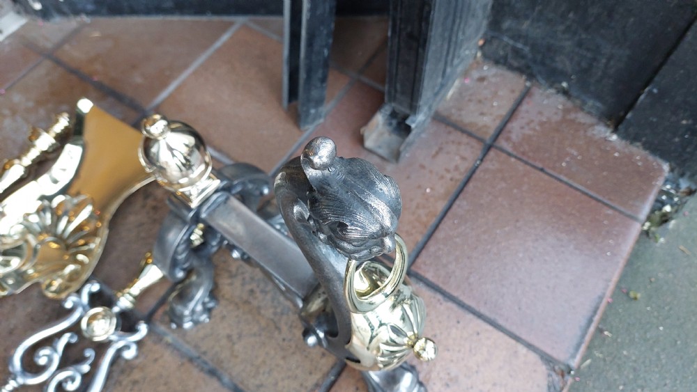 A set of Victorian hearth accessories comprising three metal fire tools resting across a pair of cast iron and brass decorated andirons. View VII