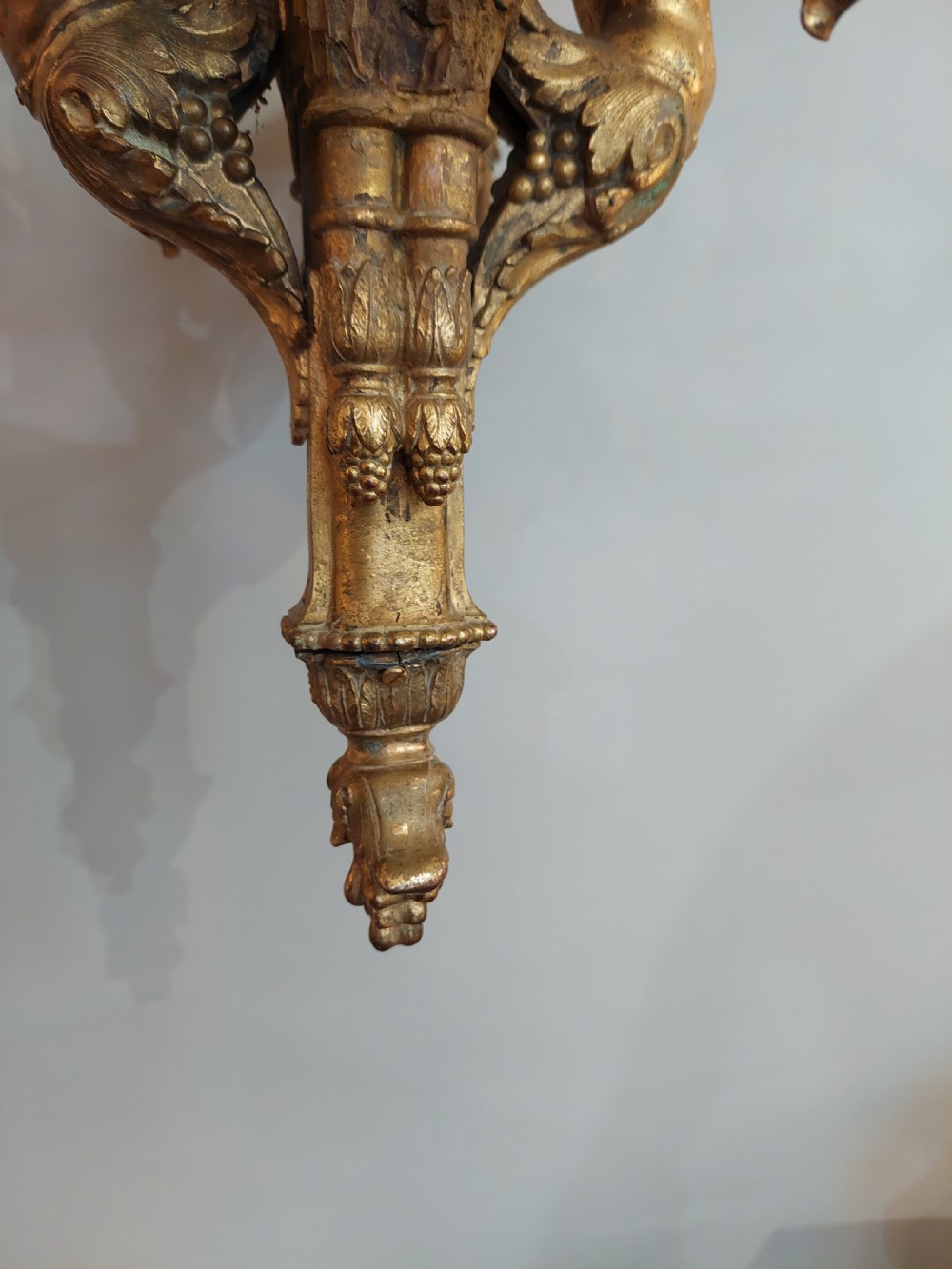 An early 20th-century six-arm gilt metal chandelier featuring carved cherub figures, scrolling acanthus leaf branches, and white candle sleeves. View III