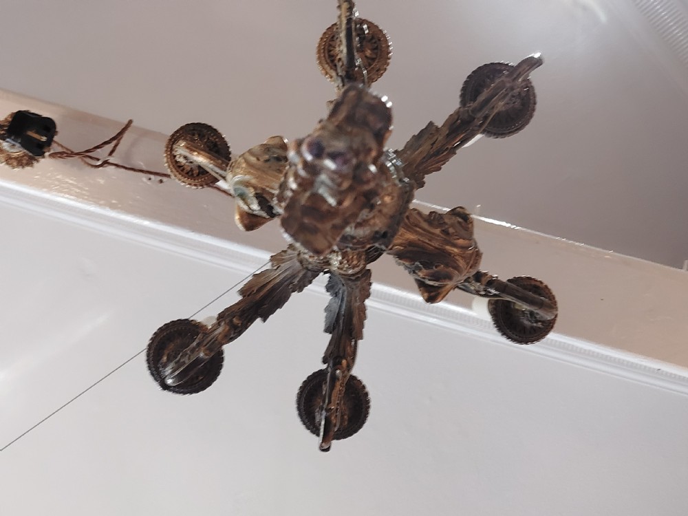 An early 20th-century six-arm gilt metal chandelier featuring carved cherub figures, scrolling acanthus leaf branches, and white candle sleeves. View IX