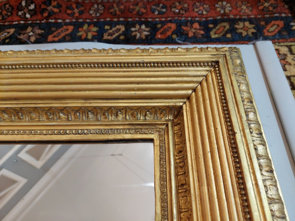 A rectangular Victorian wall mirror featuring a deep giltwood and gesso frame with ribbed moulding and beaded inner borders. View V