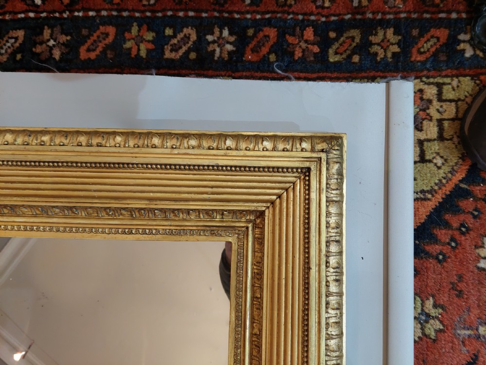 A rectangular Victorian wall mirror featuring a deep giltwood and gesso frame with ribbed moulding and beaded inner borders. View VI