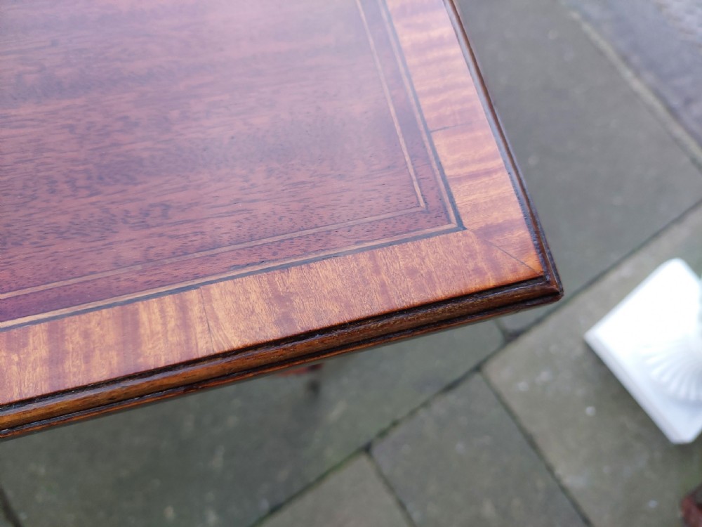 An Edwardian mahogany side table with a central oval marquetry inlay on top, fine stringing on slender tapered legs, and a shaped lower shelf. View IV