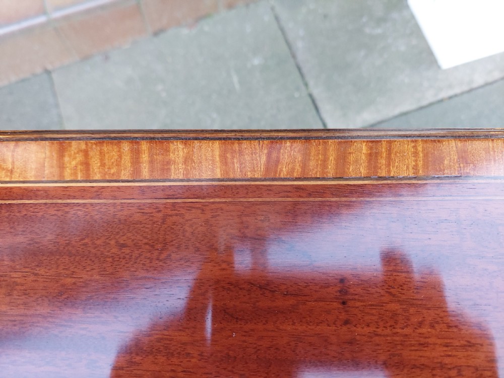 An Edwardian mahogany side table with a central oval marquetry inlay on top, fine stringing on slender tapered legs, and a shaped lower shelf. View VIII