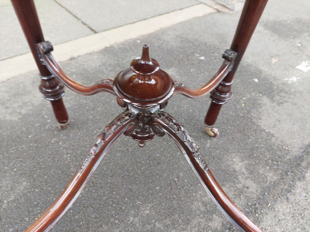 A late 19th-century mahogany centre table featuring a shaped top with marquetry inlay, turned legs, crossed stretcher with central finial, and brass castors. View III