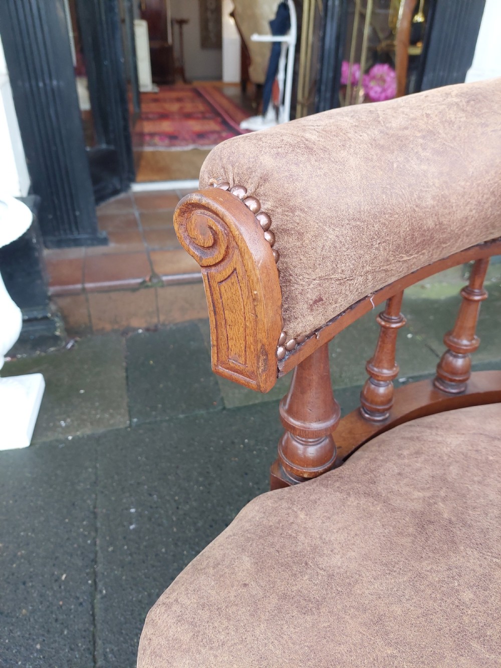 A late 19th-century walnut captains chair featuring a curved brown leather padded backrest with brass stud detailing, turned spindles, and legs set on castors. View II
