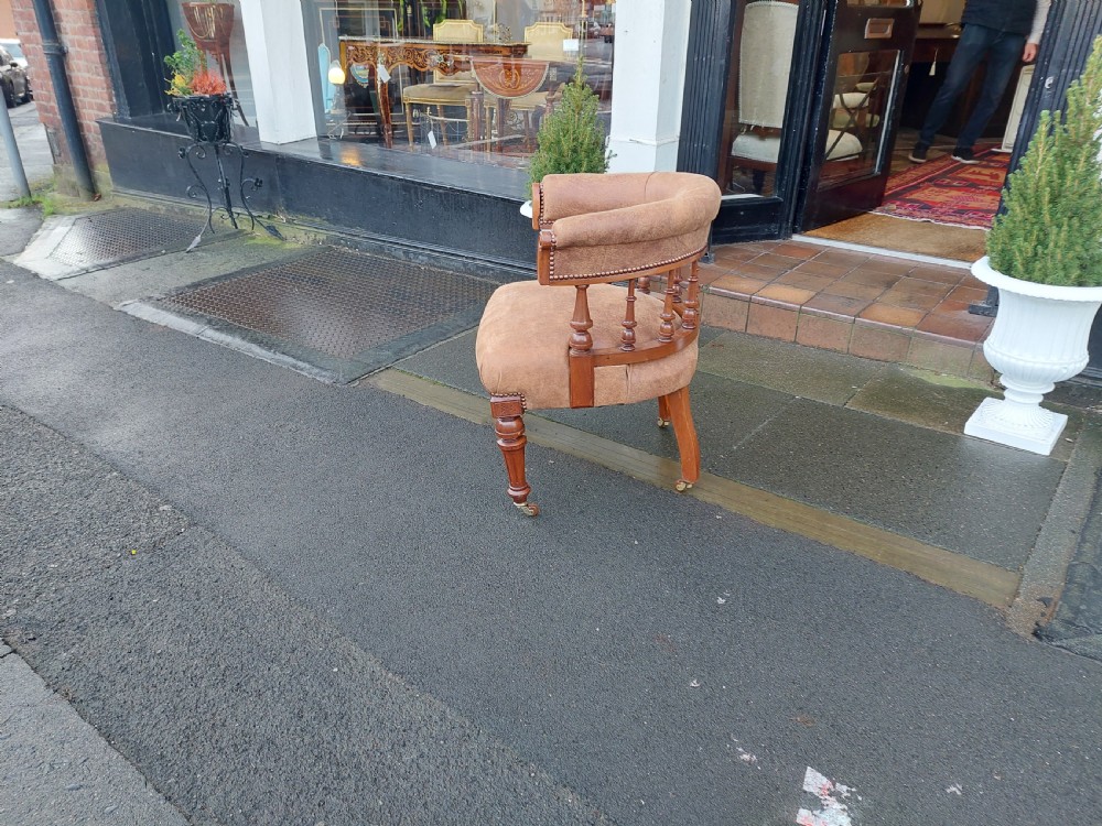 A late 19th-century walnut captains chair featuring a curved brown leather padded backrest with brass stud detailing, turned spindles, and legs set on castors. View VIII