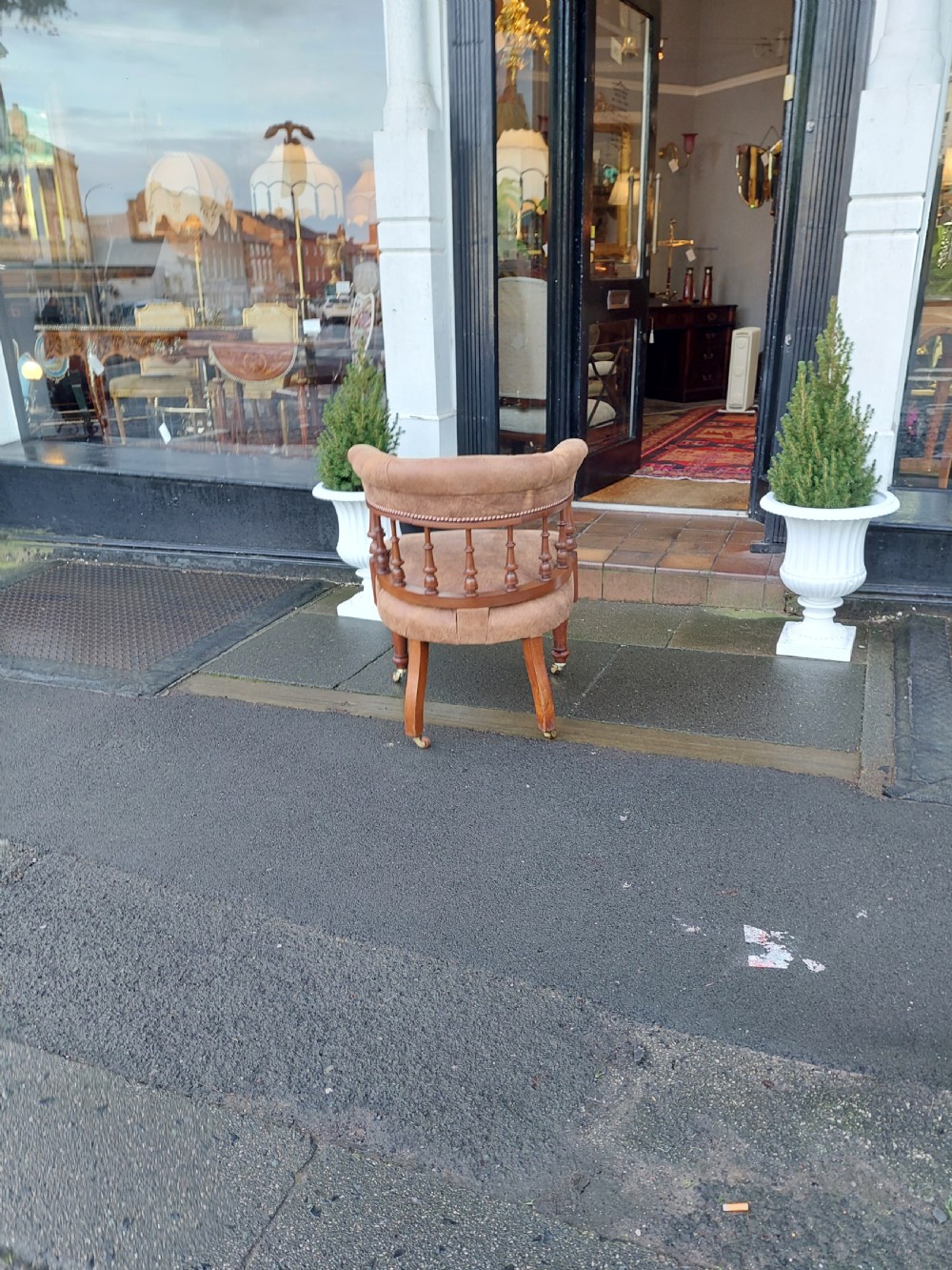 A late 19th-century walnut captains chair featuring a curved brown leather padded backrest with brass stud detailing, turned spindles, and legs set on castors. View IX