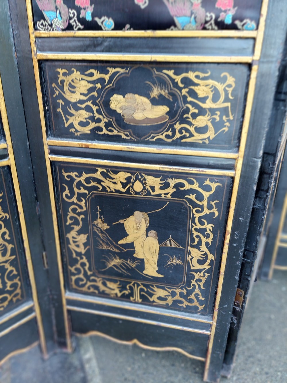 An eight-panel black lacquered folding screen with gold chinoiserie figures and floral patterned panels. View III