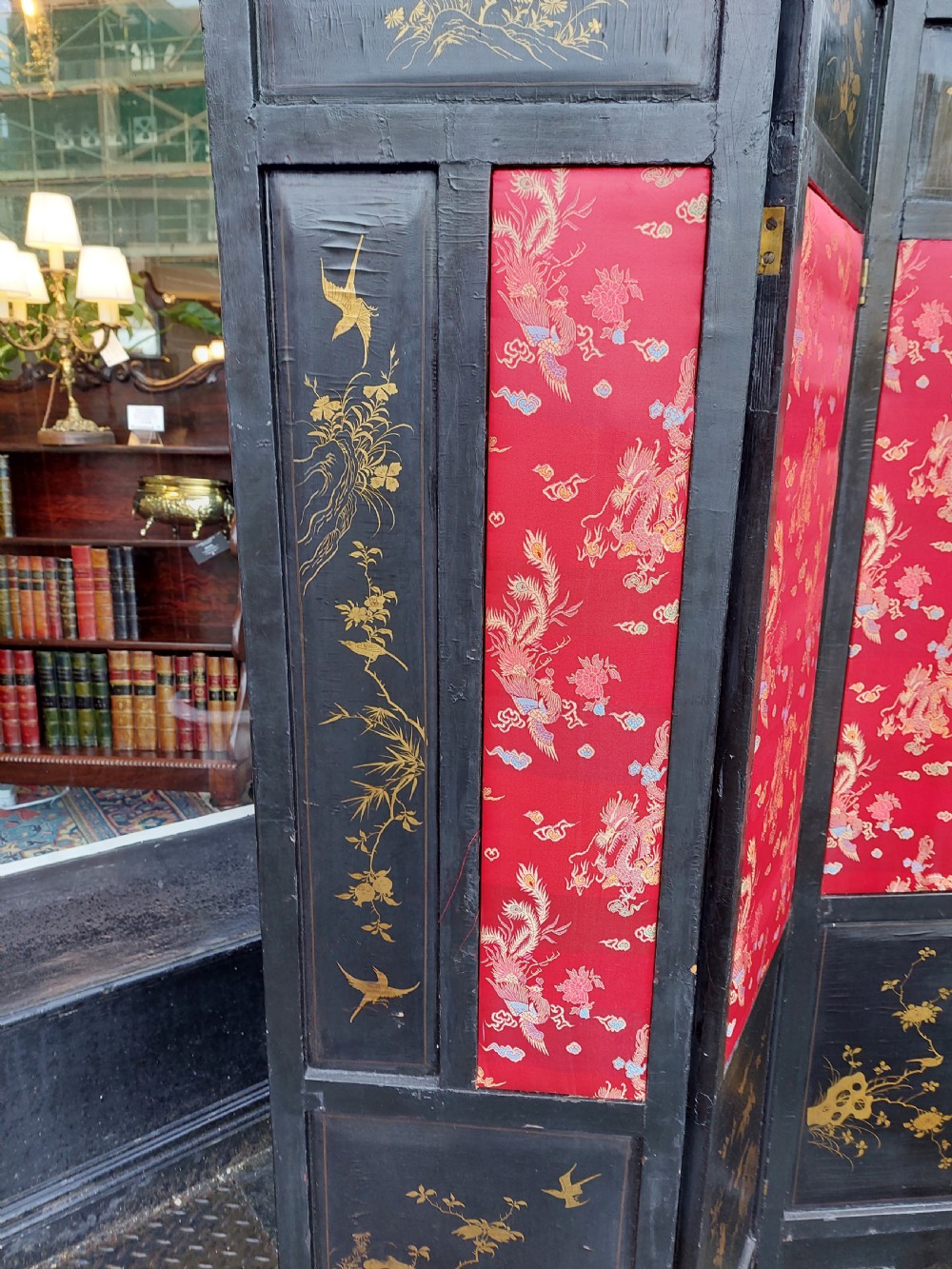 An eight-panel black lacquered folding screen with gold chinoiserie figures and floral patterned panels. View IX