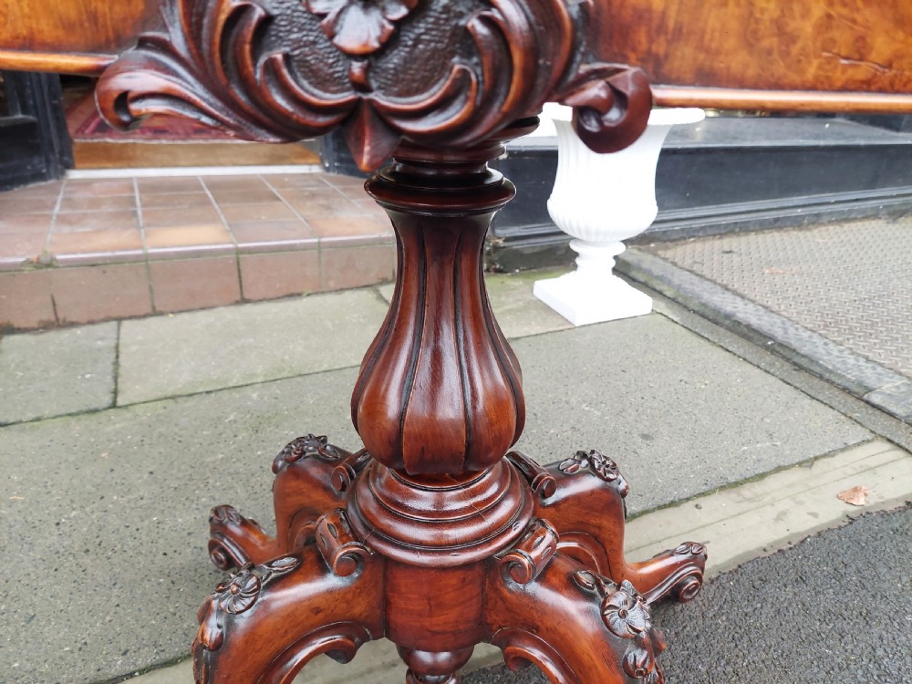 A Victorian burr walnut card table featuring a serpentine-shaped folding top resting on a carved pedestal support and quadripartite cabriole legs with castors. View III
