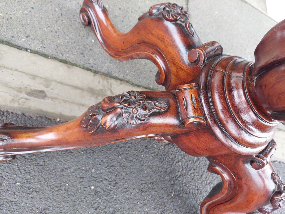 A Victorian burr walnut card table featuring a serpentine-shaped folding top resting on a carved pedestal support and quadripartite cabriole legs with castors. View VI