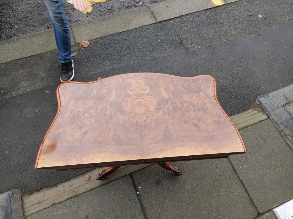 A Victorian burr walnut card table featuring a serpentine-shaped folding top resting on a carved pedestal support and quadripartite cabriole legs with castors. View VII