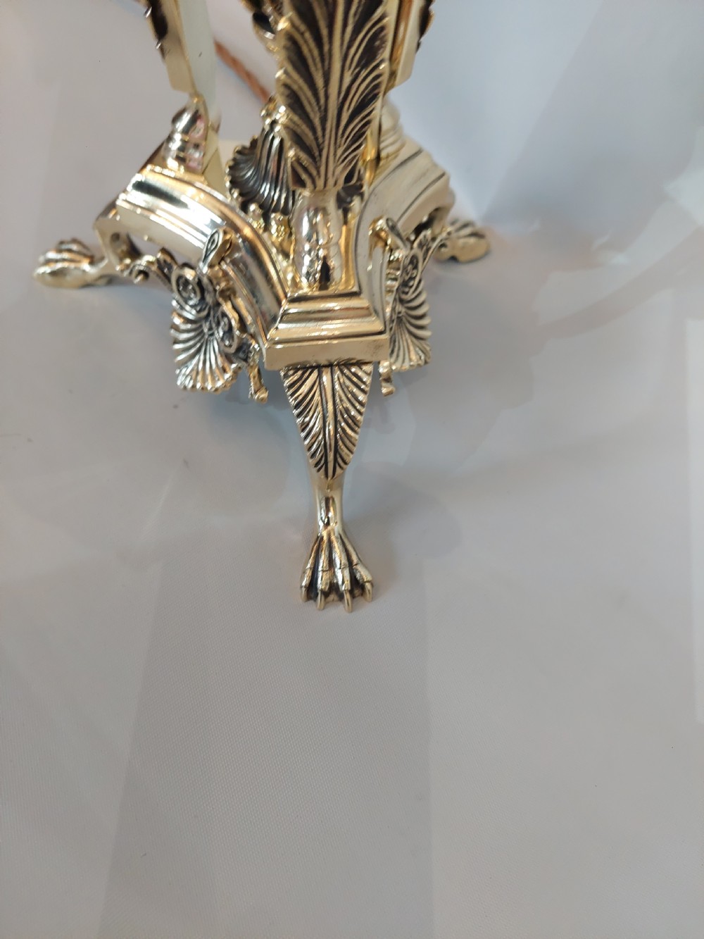 An early 20th-century brass table lamp featuring a central figure of Minerva flanked by stag head mounts, topped with a cream fringed lampshade. View III
