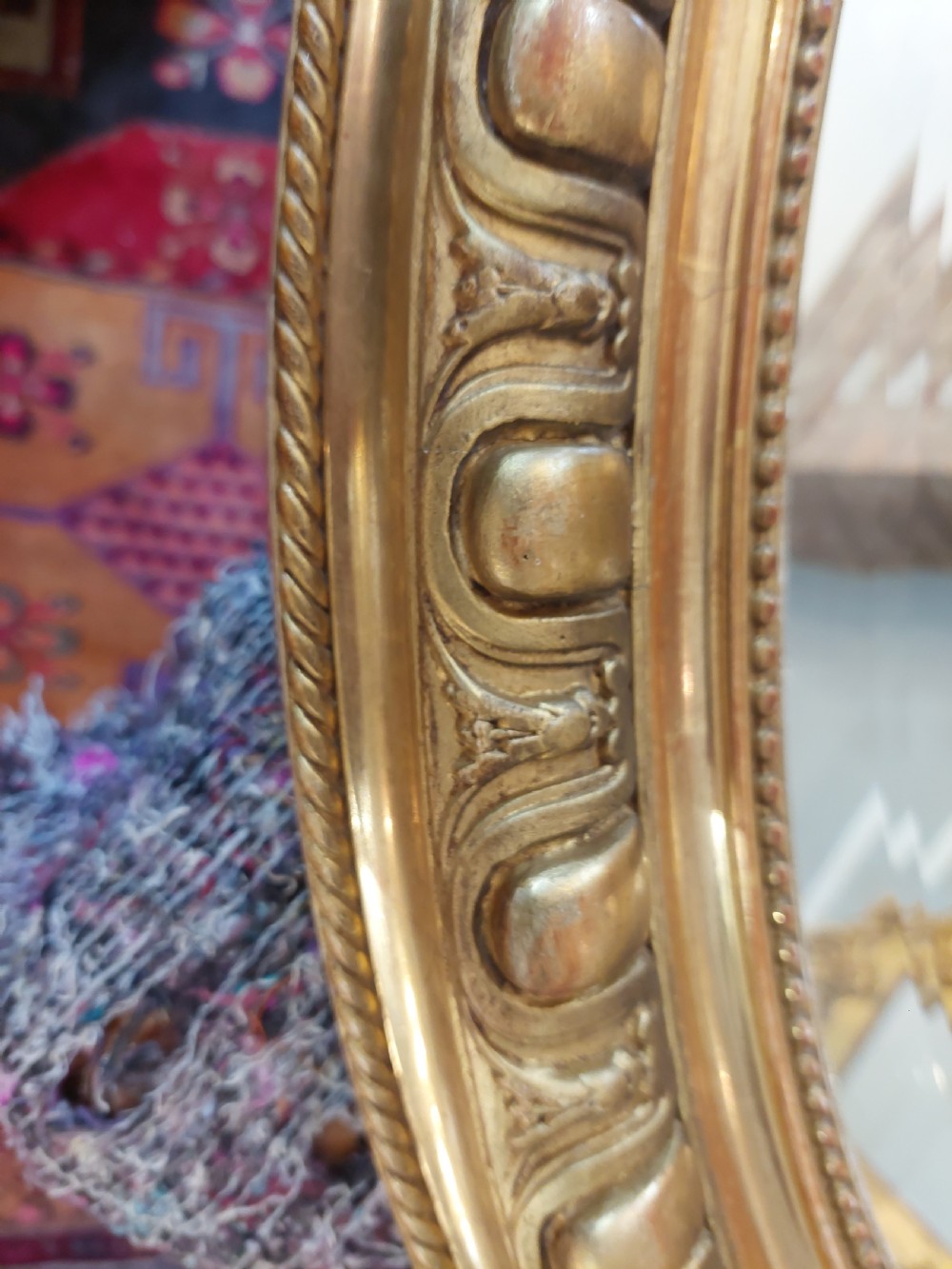 An oval Victorian Rococo style mirror featuring an ornate gilded frame with carved scrollwork, cresting, and egg-and-dart moulding. View VIII