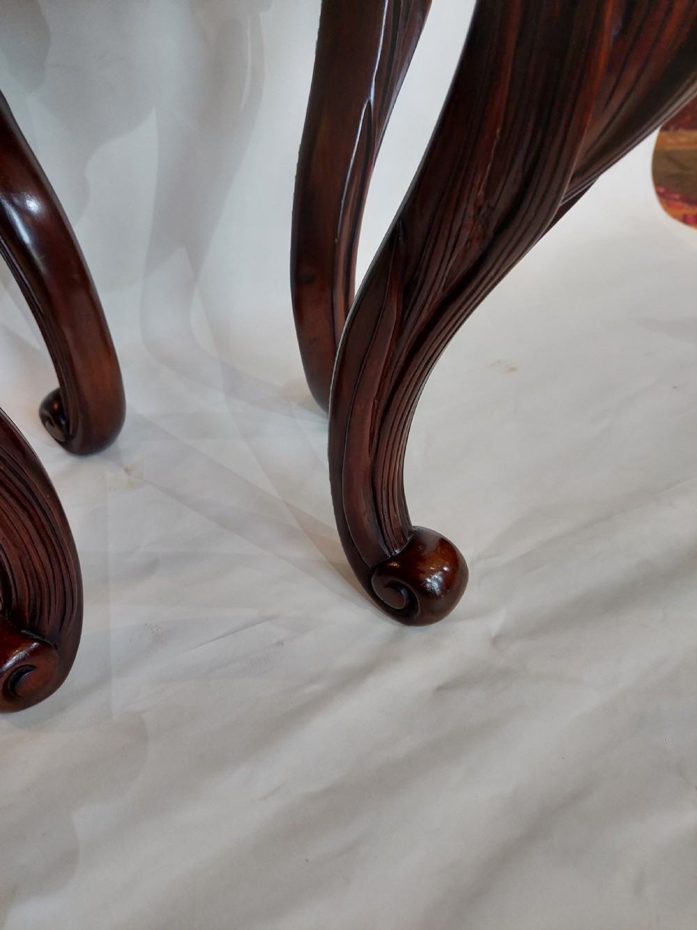 A dark mahogany circular jardiniere stand featuring elaborate floral relief carving around the deep apron and sweeping cabriole legs. View V