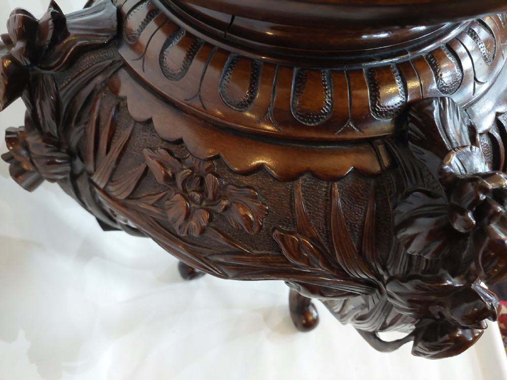A dark mahogany circular jardiniere stand featuring elaborate floral relief carving around the deep apron and sweeping cabriole legs. View VI