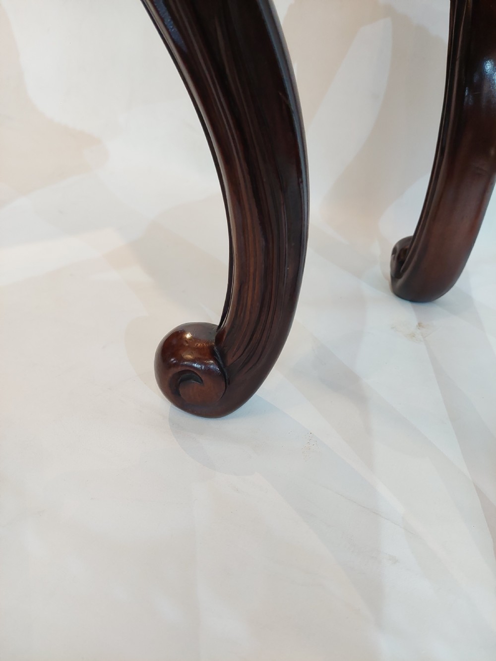 A dark mahogany circular jardiniere stand featuring elaborate floral relief carving around the deep apron and sweeping cabriole legs. View VII