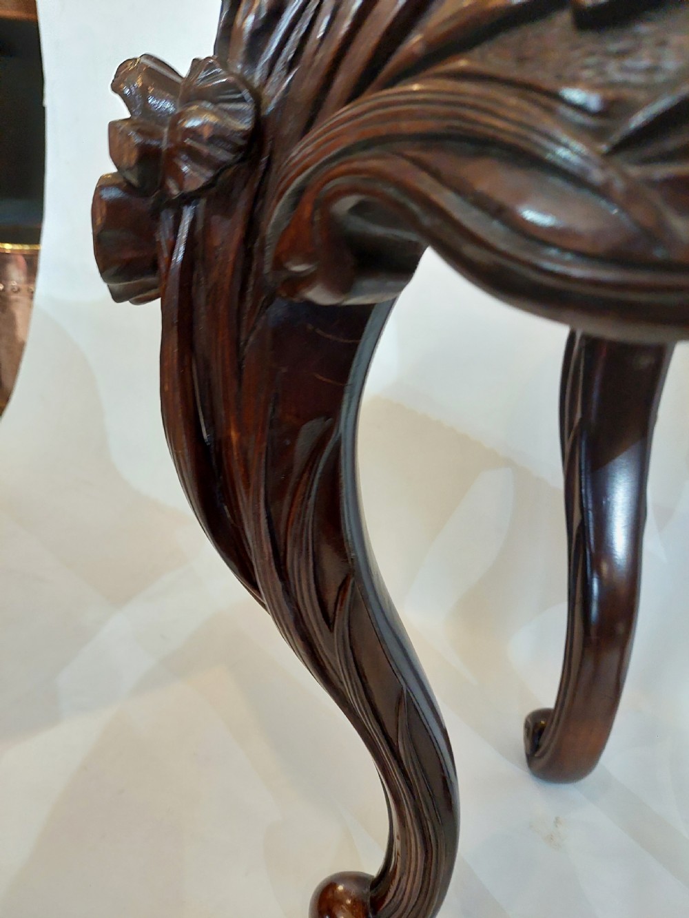 A dark mahogany circular jardiniere stand featuring elaborate floral relief carving around the deep apron and sweeping cabriole legs. View VIII