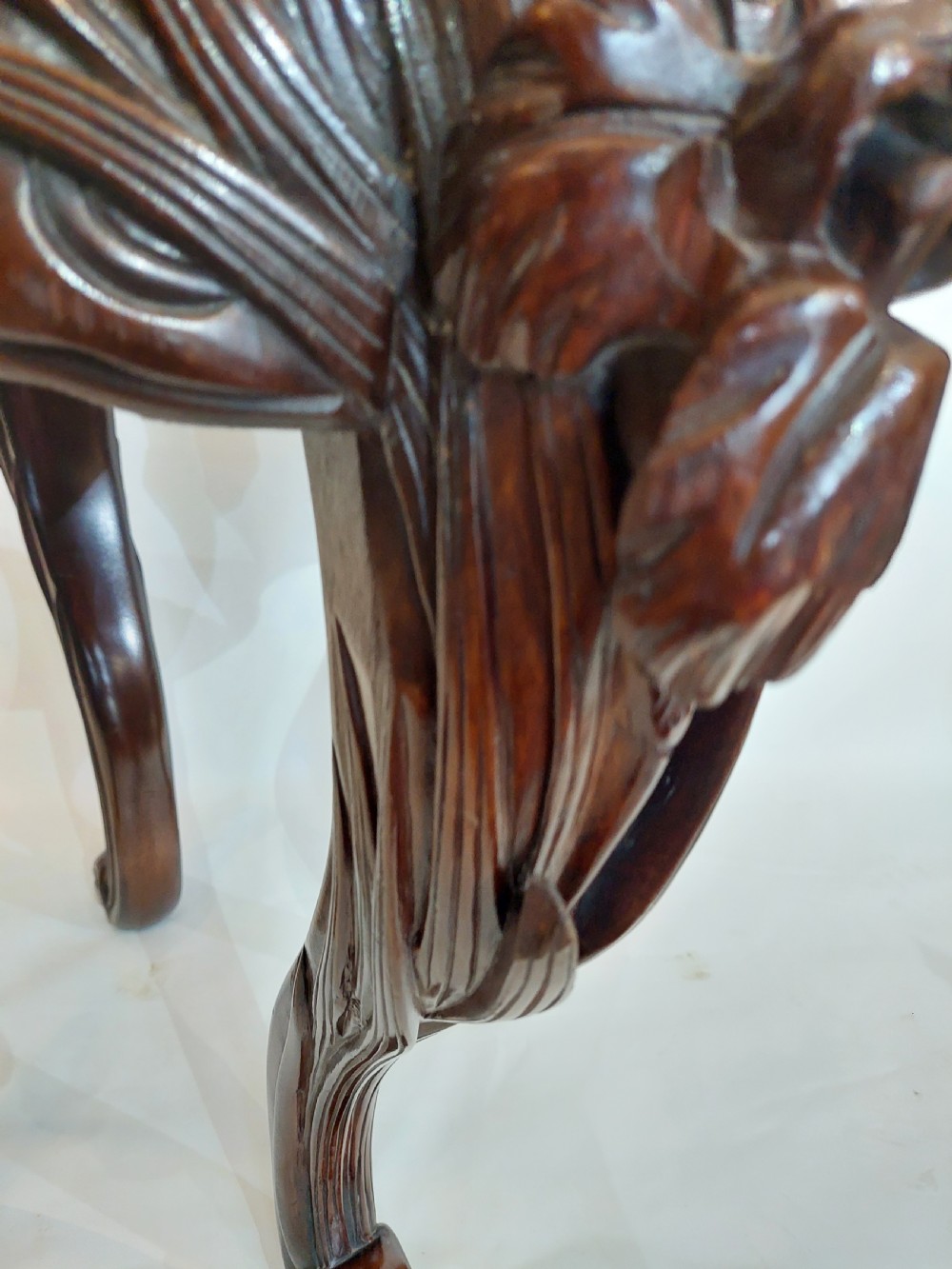 A dark mahogany circular jardiniere stand featuring elaborate floral relief carving around the deep apron and sweeping cabriole legs. View IX