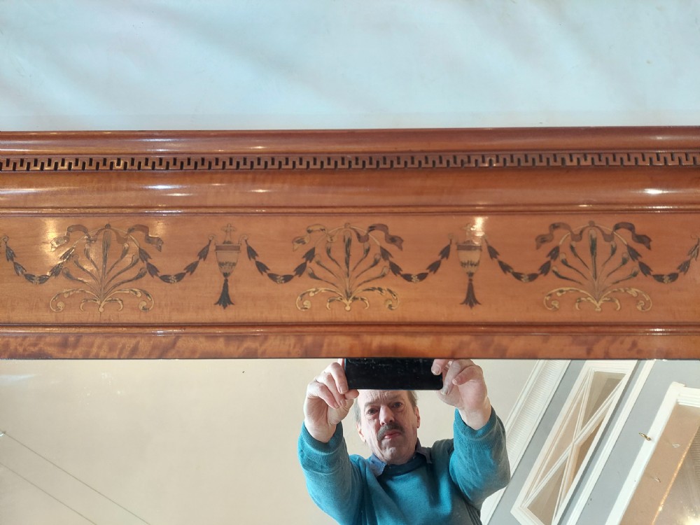 A wide satinwood overmantel mirror featuring three glass panels surrounded by a frame decorated with painted foliage swags and husk garlands. View III