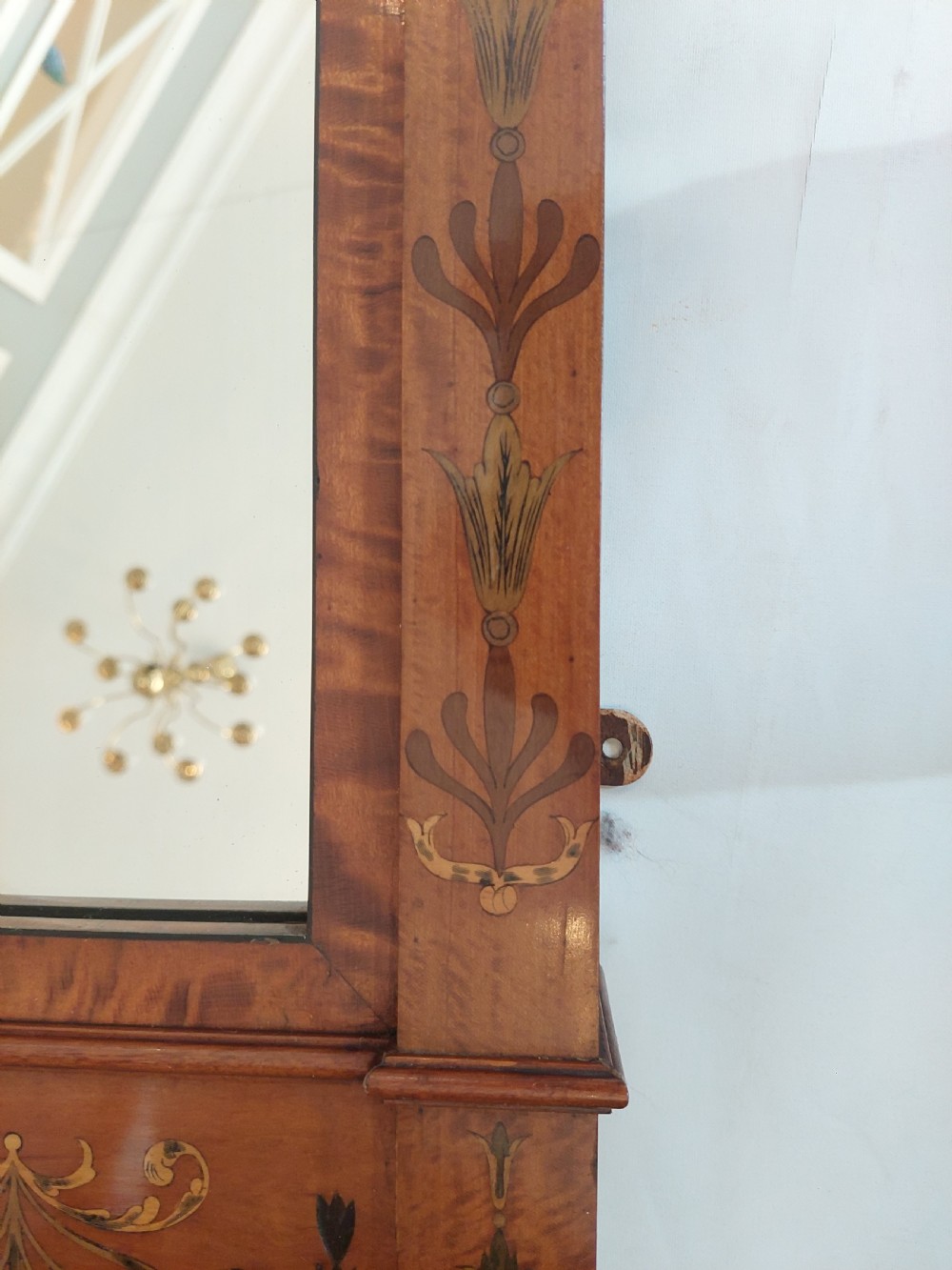A wide satinwood overmantel mirror featuring three glass panels surrounded by a frame decorated with painted foliage swags and husk garlands. View VII