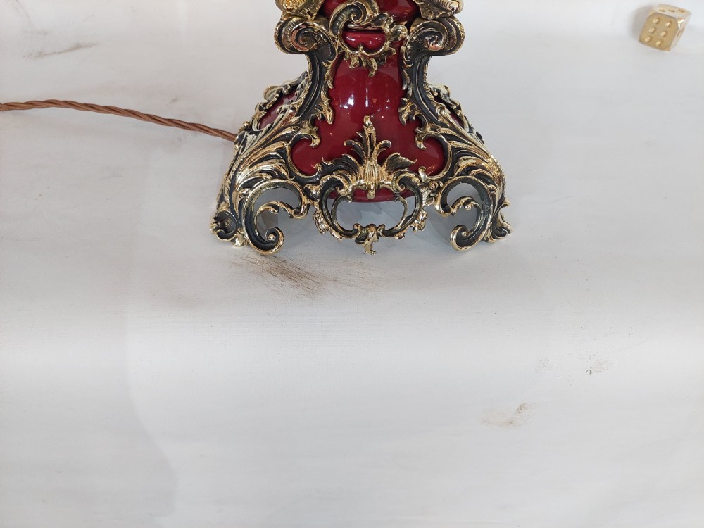 A late nineteenth-century Rococo Revival table lamp featuring a red glazed body with ornate gilt bronze scroll mounts and a red beaded fringe dome shade. View II