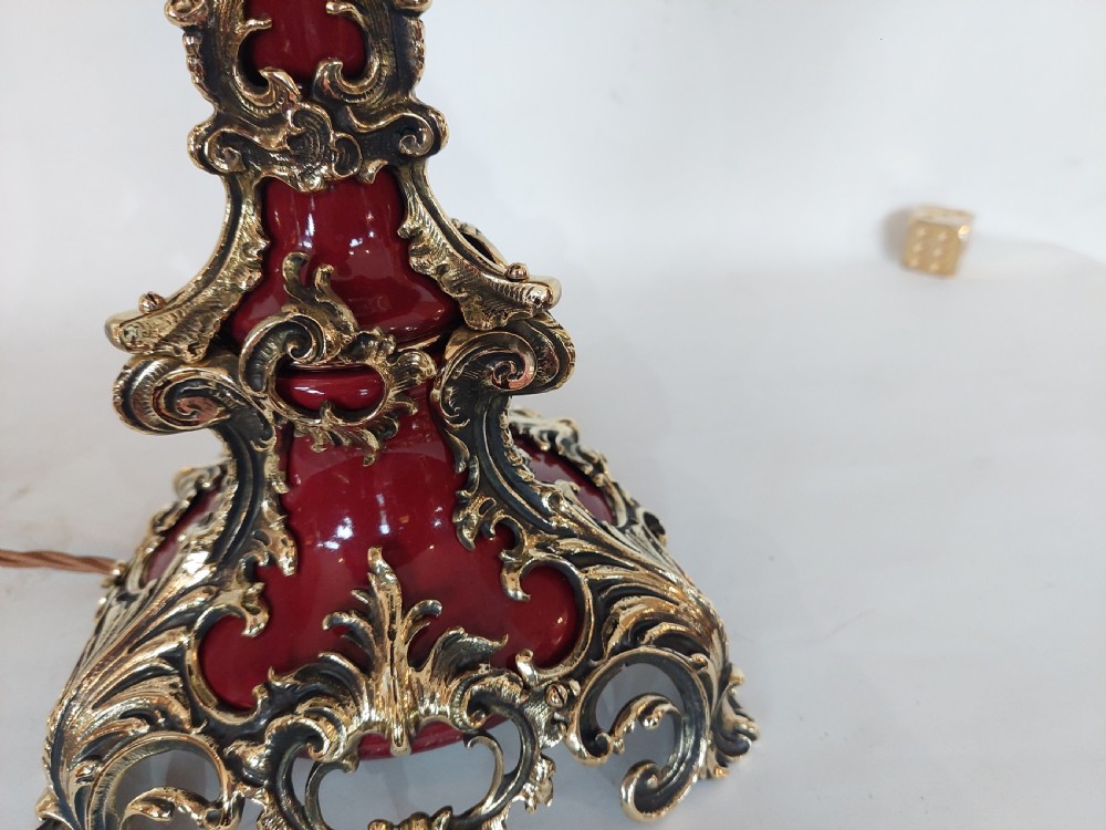A late nineteenth-century Rococo Revival table lamp featuring a red glazed body with ornate gilt bronze scroll mounts and a red beaded fringe dome shade. View III