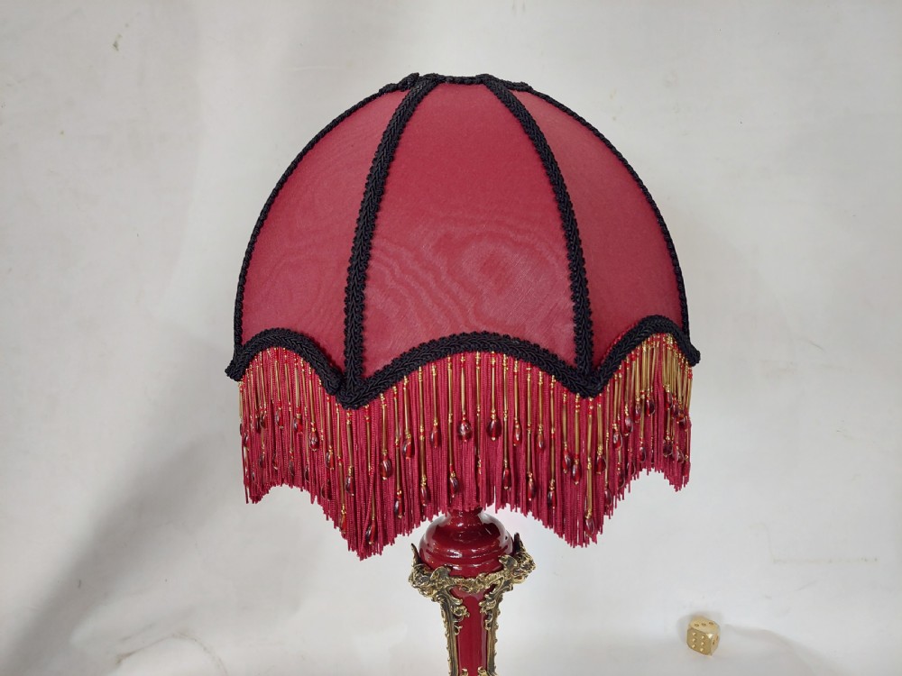 A late nineteenth-century Rococo Revival table lamp featuring a red glazed body with ornate gilt bronze scroll mounts and a red beaded fringe dome shade. View VIII