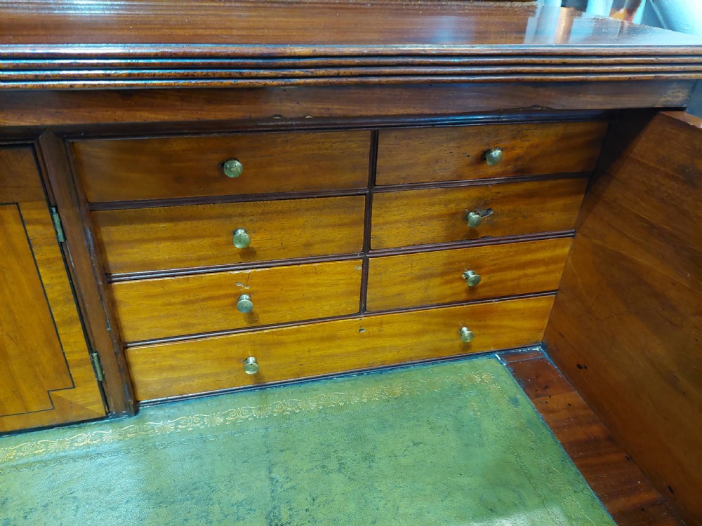 A tall Regency mahogany secretaire bookcase featuring two upper glazed doors with intricate geometric glazing bars above a chest of drawers with oval brass handles. View VI