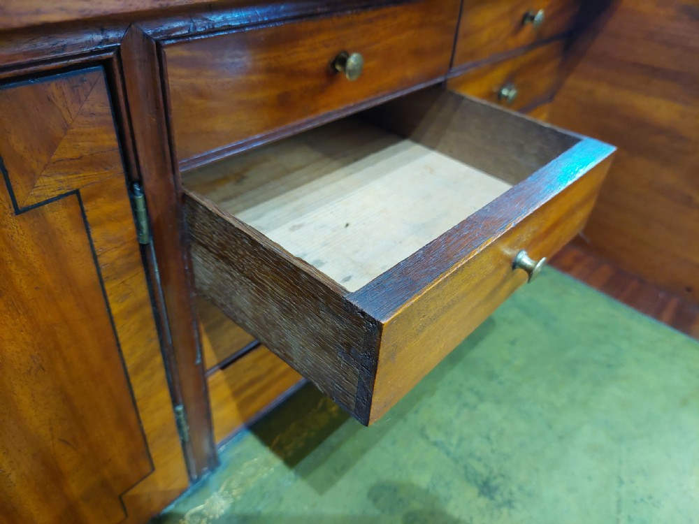 A tall Regency mahogany secretaire bookcase featuring two upper glazed doors with intricate geometric glazing bars above a chest of drawers with oval brass handles. View VII