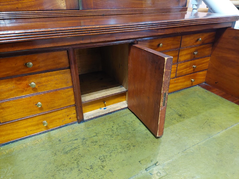 A tall Regency mahogany secretaire bookcase featuring two upper glazed doors with intricate geometric glazing bars above a chest of drawers with oval brass handles. View VIII