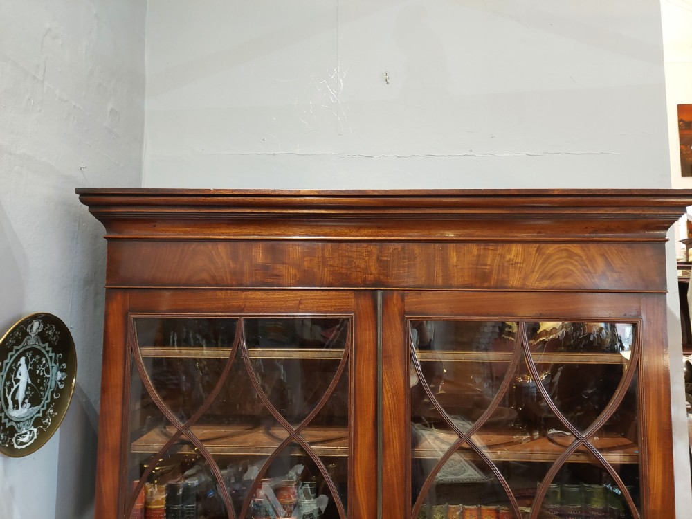 A tall Regency mahogany secretaire bookcase featuring two upper glazed doors with intricate geometric glazing bars above a chest of drawers with oval brass handles. View XIII