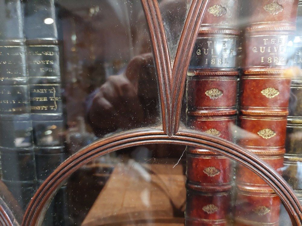 A tall Regency mahogany secretaire bookcase featuring two upper glazed doors with intricate geometric glazing bars above a chest of drawers with oval brass handles. View XV