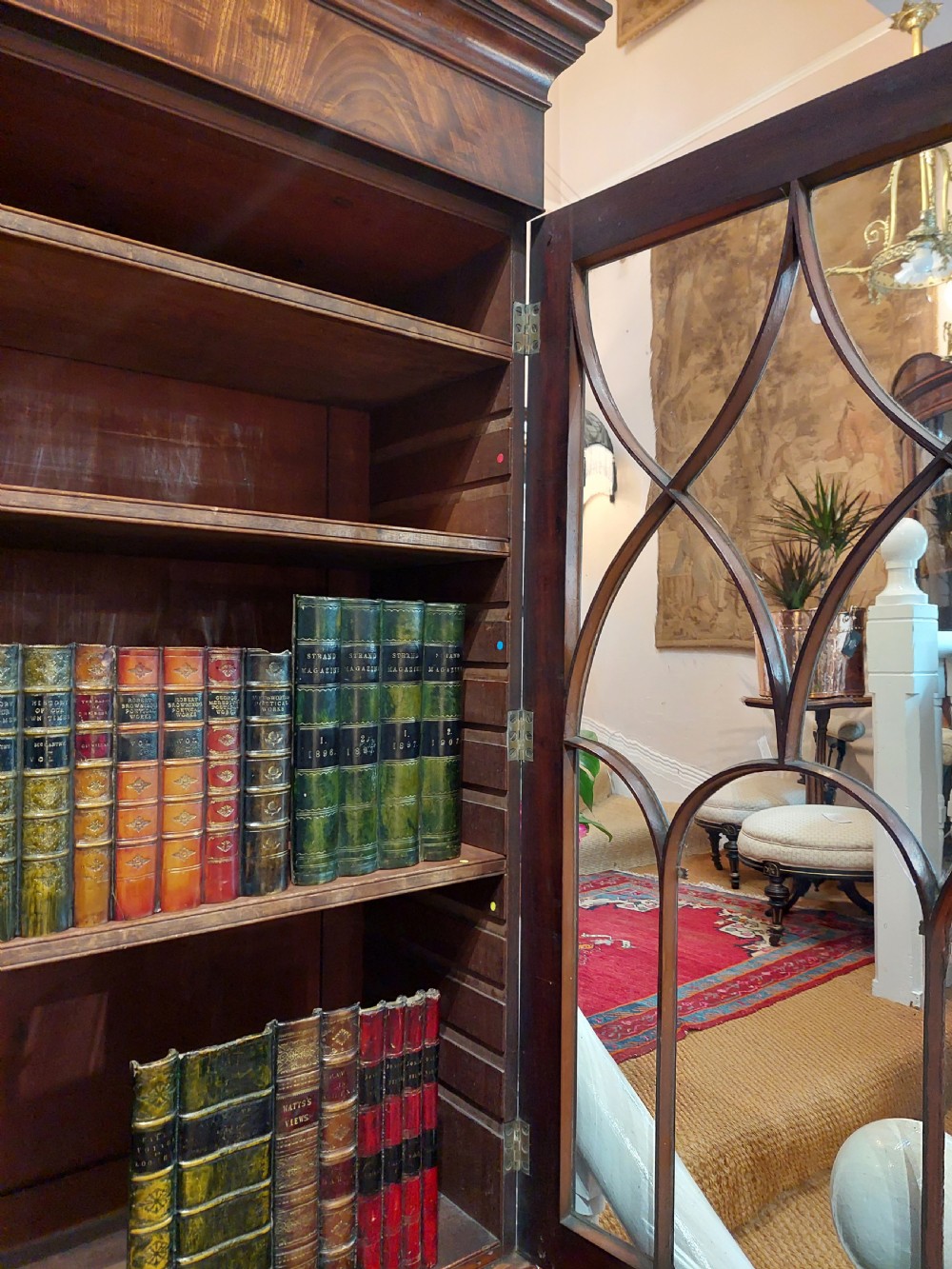 A tall Regency mahogany secretaire bookcase featuring two upper glazed doors with intricate geometric glazing bars above a chest of drawers with oval brass handles. View XVI