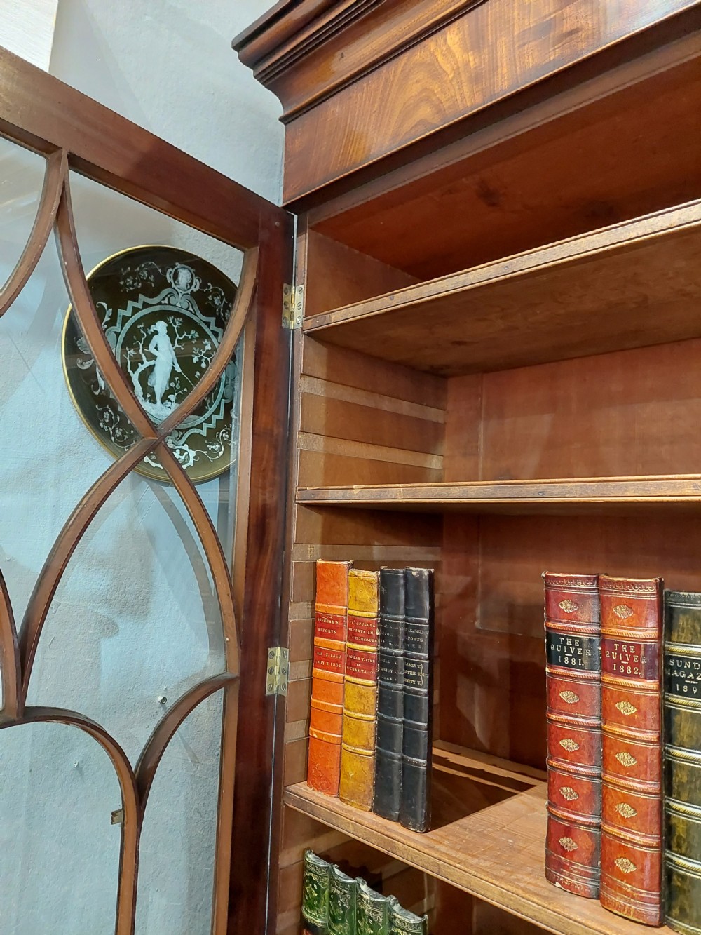 A tall Regency mahogany secretaire bookcase featuring two upper glazed doors with intricate geometric glazing bars above a chest of drawers with oval brass handles. View XVII