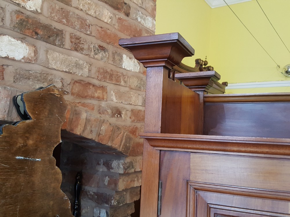 An Arts and Crafts mahogany hall robe featuring carved upper panels, two full-length doors, and a shaped top crest with corner finials. View III