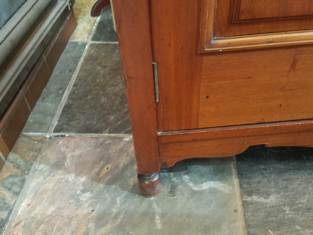 An Arts and Crafts mahogany hall robe featuring carved upper panels, two full-length doors, and a shaped top crest with corner finials. View IV