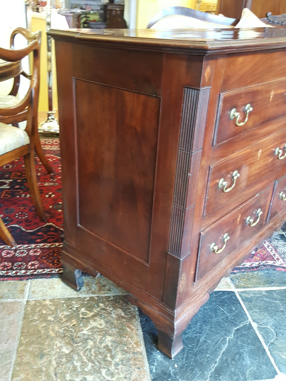 A George III mahogany Lancashire mule chest with brass swan-neck handles, fluted quarter columns, diamond keyhole inlays, and ogee bracket feet. View V
