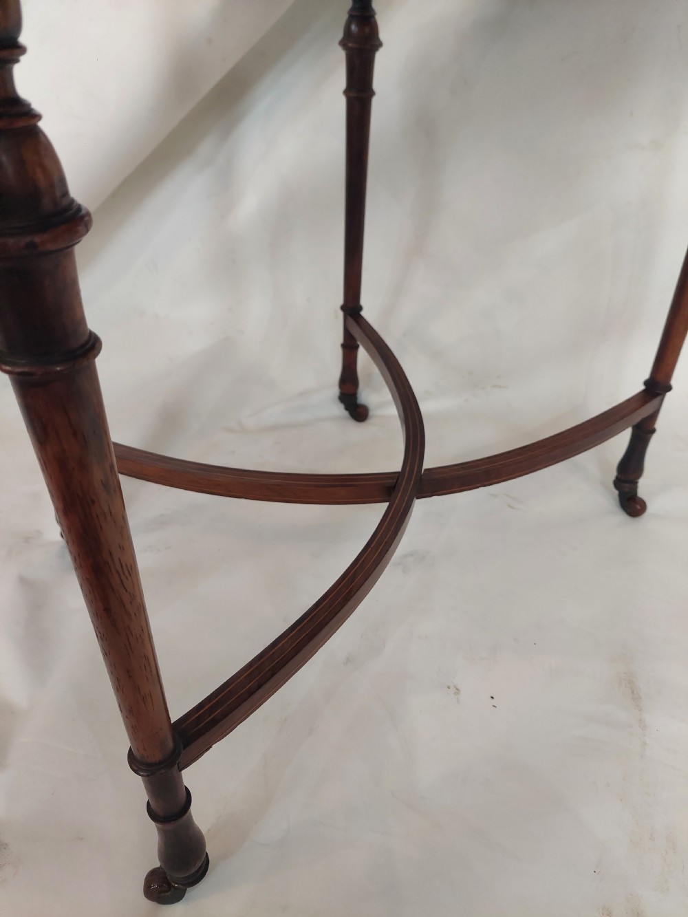 An Edwardian inlaid rosewood side table featuring a shaped top, fine line stringing, turned legs, and a curved X-form stretcher. View V