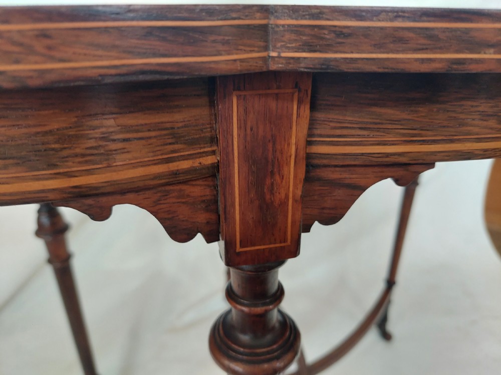 An Edwardian inlaid rosewood side table featuring a shaped top, fine line stringing, turned legs, and a curved X-form stretcher. View VI