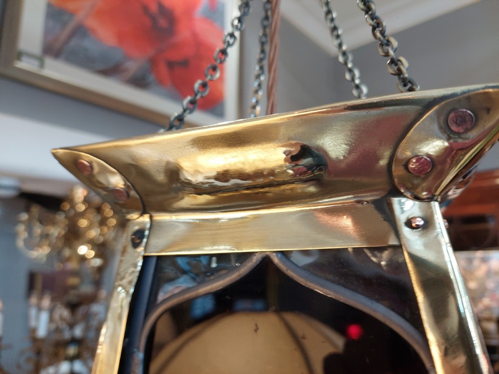 An Arts and Crafts style brass pendant lantern featuring tapered sides, suspension chains, and leaded stained glass panels decorated with stylized botanical motifs. View V